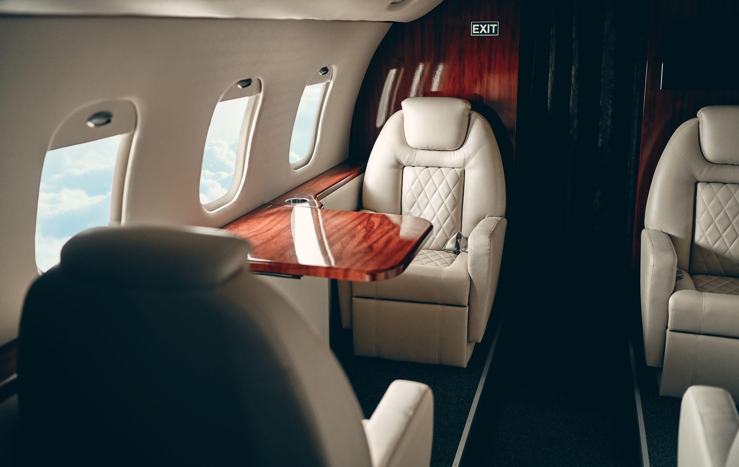 Cream club seats and a wood table in a quiet jet cabin
